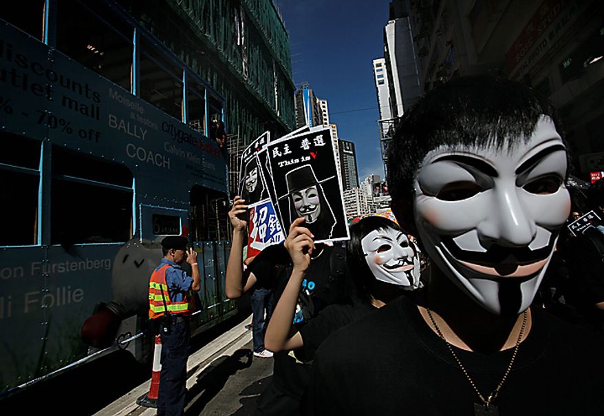 Protesters wearing masks raise placards with Chinese words that read " Democracy, Universal Suffrage" in the annual pro-democracy march demanding universal suffrage in a downtown Hong Kong street on Thursday, July 1, 2010. The pro-democracy camp's annual July 1 march is supposed to demonstrate unity on the anniversary of the former British colony's reversion to Chinese rule. (AP Photo/Vincent Yu)
