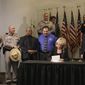 ** FILE ** Arizona Gov. Jan Brewer, with law enforcement supporters behind her, signs immigration bill SB 1070 into law in Phoenix on April 23, 2010. (AP Photo)