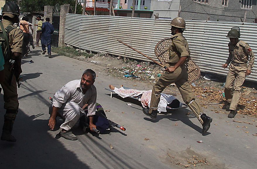 Indian policemen chase Kashmiri mourners as the dead bodies of Muzaffar Bhat and Fayaz Ahamed Wani lie unattended on the ground during their funeral procession on the outskirts of Srinagar, India, Tuesday, July 6, 2010. Government forces fired on hundreds of rock-throwing protesters in Indian Kashmir on Tuesday, killing Wani and wounding two others as a seven-day curfew was lifted, locals and officials said. Bhat was allegedly killed by paramilitary soldiers Monday (AP Photo/Mukhtar Khan)