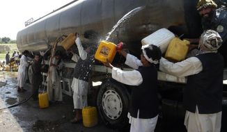 Afghans collect fuel from a tanker shot up in an attack on a NATO supply convoy in Baghlan province, north of Kabul, Afghanistan, Tuesday, July 6, 2010. (AP Photo)
