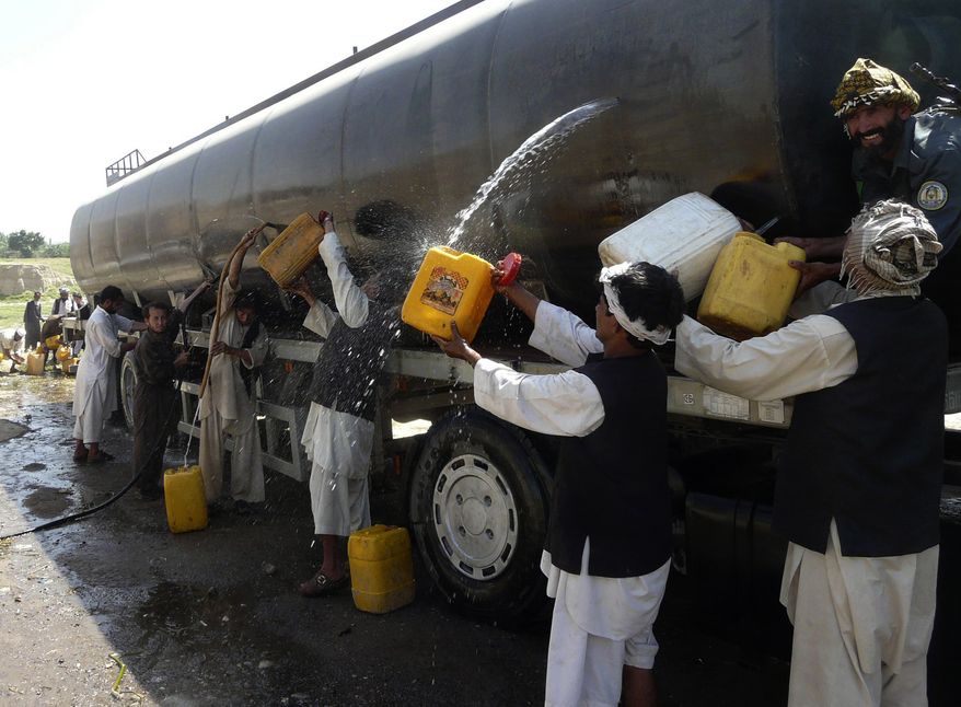 Afghans collect fuel from a tanker shot up in an attack on a NATO supply convoy in Baghlan province, north of Kabul, Afghanistan, Tuesday, July 6, 2010. (AP Photo)
