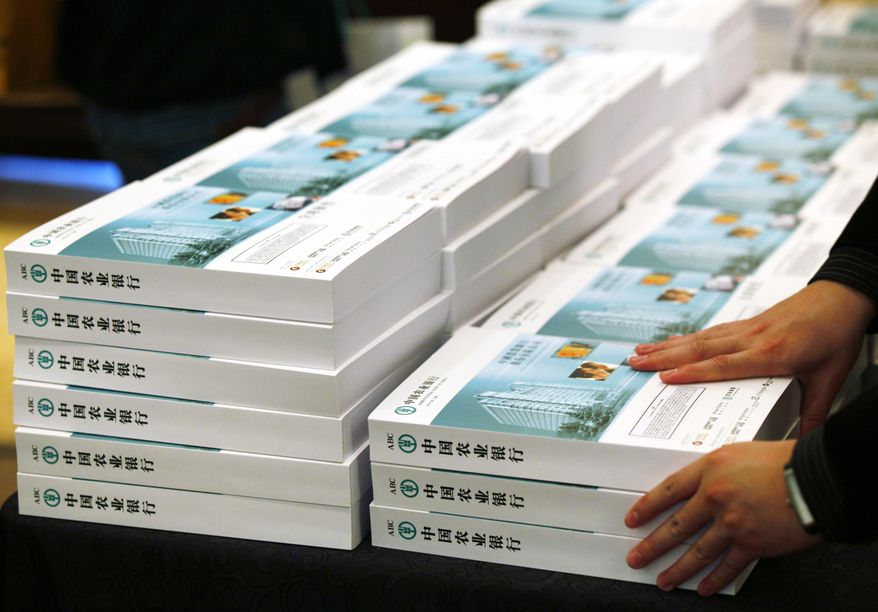 An employee of the Agricultural Bank of China arranges the prospectus during a news conference on its initial public offering in Hong Kong Tuesday, June 29, 2010. The bank of China expects to reap up to U.S. $23.2 billion in the world's largest share listing after capping the price range for its shares at a much lower level than originally expected. (AP Photo/Kin Cheung)