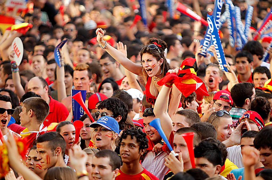 Soccer fans react before the start of the World Cup semifinal soccer match between Spain and Germany shown on a large screen outside the Santiago Bernabeu stadium in Madrid, on Wednesday, July 7, 2010. (AP Photo/Paul White)