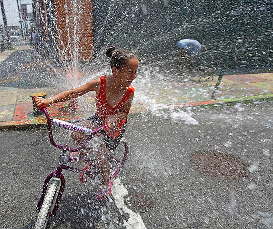 A person cools off in spraying water from a fire hydrant in the Kensington neighborhood of Philadelphia, Tuesday, July 6, 2010. The East Coast broiled under an unforgiving sun Tuesday as the temperature soared above 100 degrees in several cities. (AP Photo/Matt Rourke)