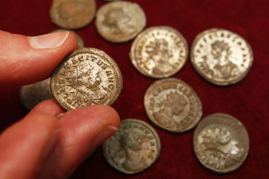 A staff member displays a coin of Tetricus I (AD271-4 ) on display at the British Museum in London, Thursday, July 8, 2010. About 52,500 Roman coins were found in a large pot by a British treasure hunter Dave Crisp using a metal detector in a field in southwest England, one of the largest treasure hoards ever found in Britain. (AP Photo/Sang Tan)