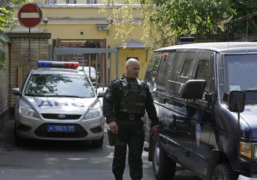 A traffic police car guards an entrance, as an armored vehicle and a riot police officer in a heavy gear leave the Lefortovo prison in Moscow, Thursday, July 8, 2010. Riot police on Thursday secured the perimeter of the prison, and convoy of armored vehicles arrived in the morning at the prison, thought to be the central gathering point for people convicted of spying for the West, including nuclear researcher Igor Sutyagin, serving a 14-year sentence for spying for the United States. (AP Photo/Misha Japaridze)
