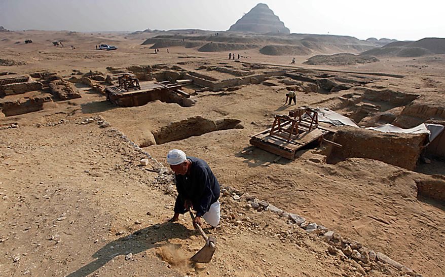 With the Step Pyramid of King Djoser in the background, an Egyptian laborer works at the site of the unearthed 4,300-year-old tombs of Khonsu and his father Shendwas, both of whom served as heads of the royal scribes during the Old Kingdom, in Saqqara near Cairo, Egypt, Thursday, July 8, 2010. Egyptian archaeologists have unveiled their latest discovery - two 4,300-year-old tombs carved out of stone and unearthed in the ancient necropolis of Saqqara near Cairo. (AP Photo/Nasser Nasser)