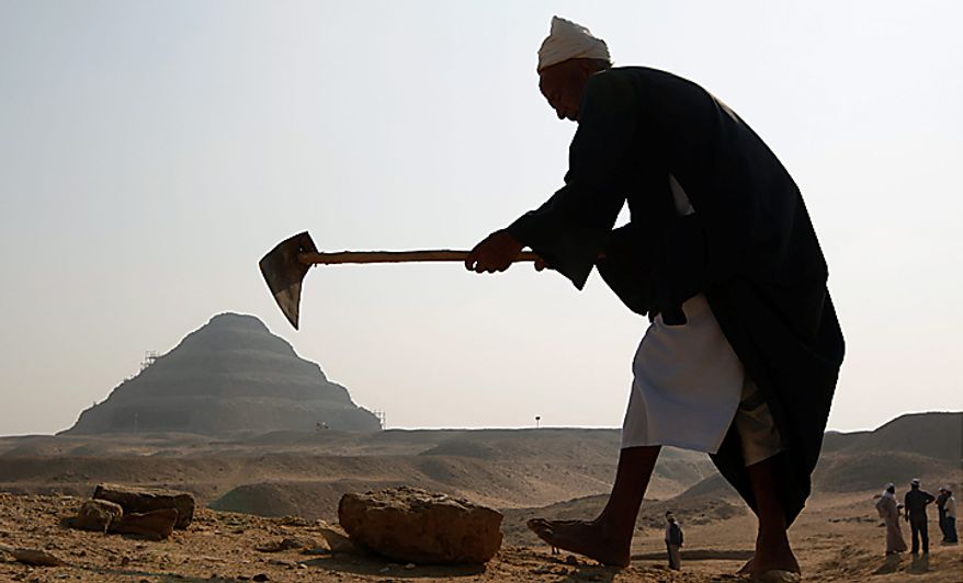 With the Step Pyramid of King Djoser in the background, an Egyptian labors at the site of the unearthed 4,300-year-old tombs of Khonsu and his father Shendwas, both of whom served as heads of the royal scribes during the Old Kingdom, in Saqqara near Cairo, Egypt ,Thursday, July 8, 2010. Egyptian archaeologists have unveiled their latest discovery, two 4,300-year-old tombs carved out of stone and unearthed in the ancient necropolis of Saqqara near Cairo. (AP Photo/Nasser Nasser)