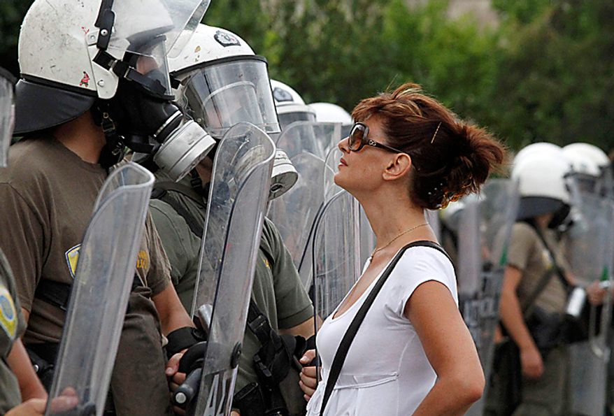 A protester confronts riot police outside parliament during a rally in central Athens, Thursday, July 8, 2010. The Greek government is battling growing discontent over a new round of economic austerity, with fresh strikes, public hostility, and party dissent testing the nation's ability to make it out of its debt crisis. Unions on Thursday staged their sixth general strike this year _ halting public transport and services, stopping ferry departures and closing schools, newspapers, courts and public hospitals. (AP Photo/Dimitri Messinis)