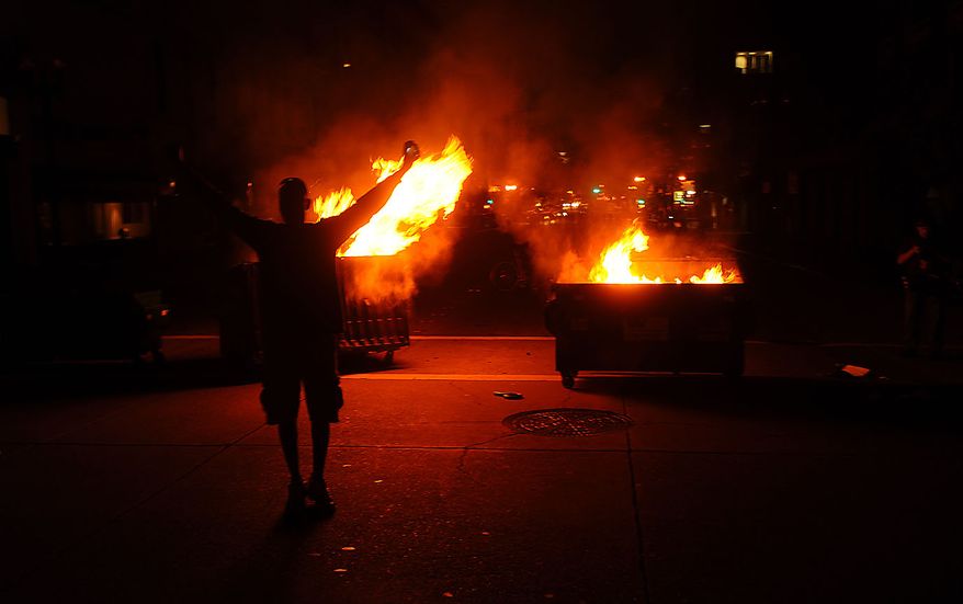 A man celebrates as dumpsters burn in Oakland, Calif., following an involuntary manslaughter verdict in Johannes Mehserle's trial on Thursday, July 8, 2010. A former transit police officer, Mehserle shot and killed unarmed black man Oscar Grant on New Year's Day 2009. (AP Photo/Noah Berger)