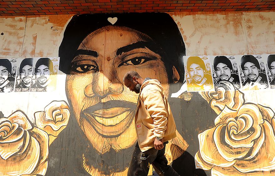 A pedestrian passes a mural of Oscar Grant in Oakland, Calif., shortly before a jury delivered an involuntary manslaughter verdict in Johannes Mehserle's trial on Thursday, July 8, 2010. (AP Photo/Noah Berger)