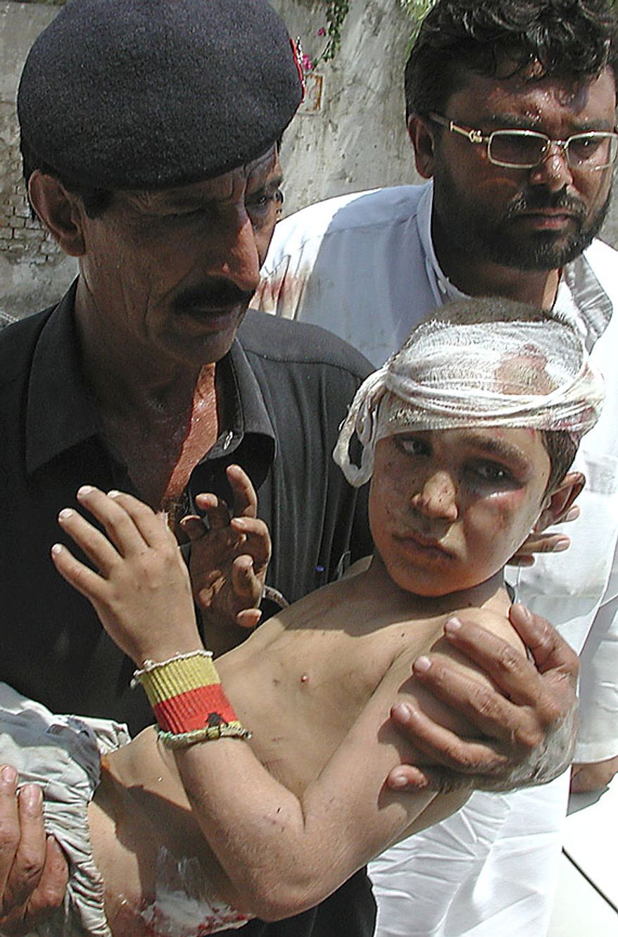 A Pakistani hospital guard carries an injured child to a local hospital in Peshawar, Pakistan on Friday, July 9, 2010. Two suicide bombers, at least one of them on a motorcycle, struck outside a government office Friday in a tribal region where Pakistan's army has fought the Taliban, killing scores of people and left many injured, officials said. (AP Photo/Mohammad Iqbal)