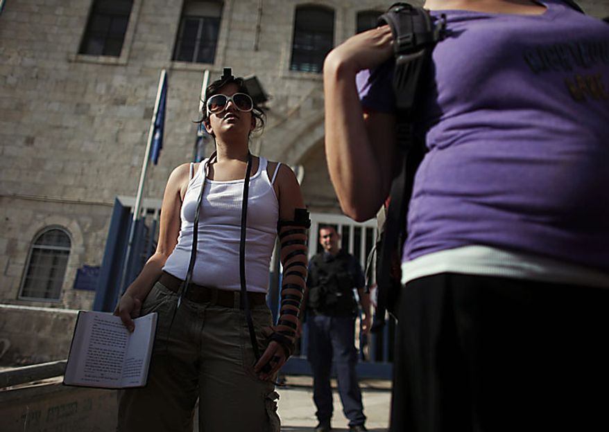 An Israeli member of the Women of the Wall organization prays outside a police station after Anat Hoffman, not pictured, the chairwoman of their organization, was detained outside the Western Wall, Judaism's holiest site, in Jerusalem's Old City, Monday, July 12, 2010. Ms. Hoffman was arrested for carrying a biblical scroll at a Judaism's holiest site on Monday in contravention of an Israeli high court ruling that bars women from carrying the holy texts in the area of the Western Wall, said police spokesman Micky Rosenfeld. (AP Photo/Tara Todras-Whitehill)