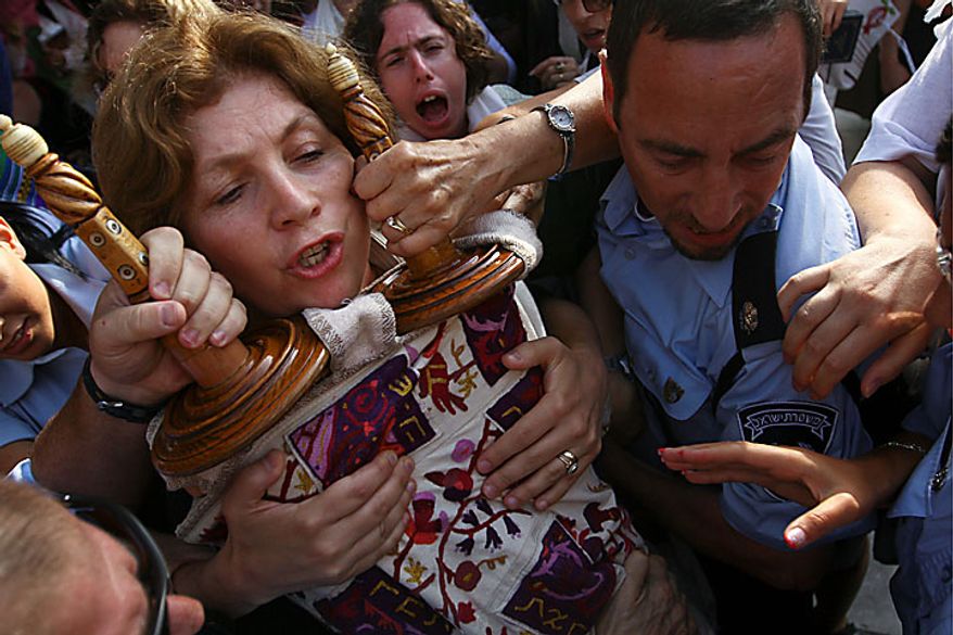 Anat Hoffman, left, chairwoman of the Women of the Wall organization, holds on to a Torah scroll as Israeli police attempt to take it from her and detain her outside the Western Wall, Judaism's holiest site, Monday, July 12, 2010. Ms. Hoffman was arrested for carrying a biblical scroll at a Judiasm's holiest site on Monday in contravention of an Israeli high court ruling that bars women from carrying the holy texts in the area of the Western Wall, said police spokesman Micky Rosenfeld. (AP Photo/Tara Todras-Whitehill)