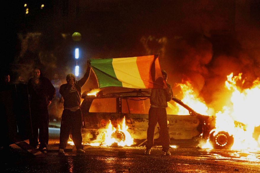 Nationalist protesters brandish the Irish flag during clashes with police in Belfast on Monday. Police struggled to quell rioting by Irish Catholic nationalists after a day of mass Protestant parades. (Associated Press)