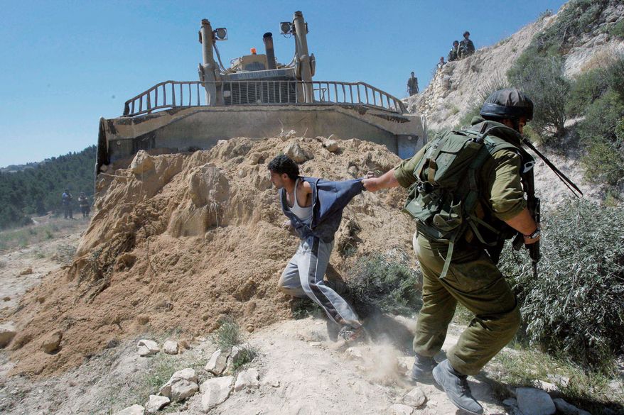 A demonstration in April erupts in a scuffle between an Israeli soldier and a Palestinian who was protesting the construction of a barrier that makes it difficult for Palestinians to reach farmland, schools and medical care. (Associated Press)