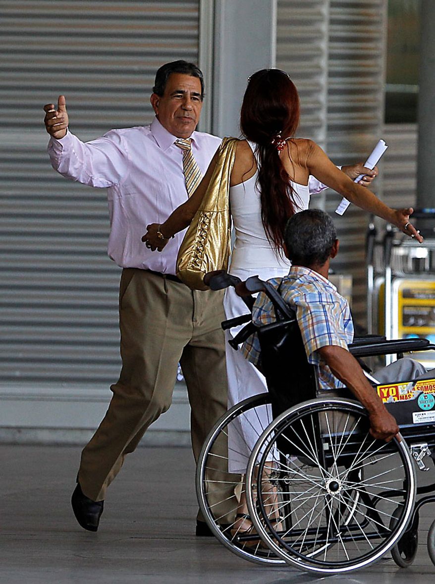 Cuban dissident Julio Cesar Galvez Rodriguez, left, greets an unidentified person after arriving at Madrid's Barajas airport on Tuesday, July 13, 2010. Seven Cuban political prisoners and members of their families arrived in Madrid on Tuesday, the first of a group of inmates the government in Havana has promised to release, an official said. It was the start of a mass liberation of dissidents promised by Cuba's actions that once seemed unthinkable. (AP Photo/Victor R. Caivano)