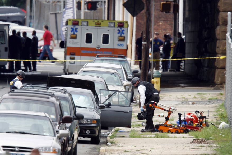 Authorities search a car for a suspected bomb near a railroad overpass in Newark, N.J., on Wednesday, July 14, 2010. A mechanical robot and the red gas cans it removed from the car sit nearby. (AP Photo/Mel Evans)
