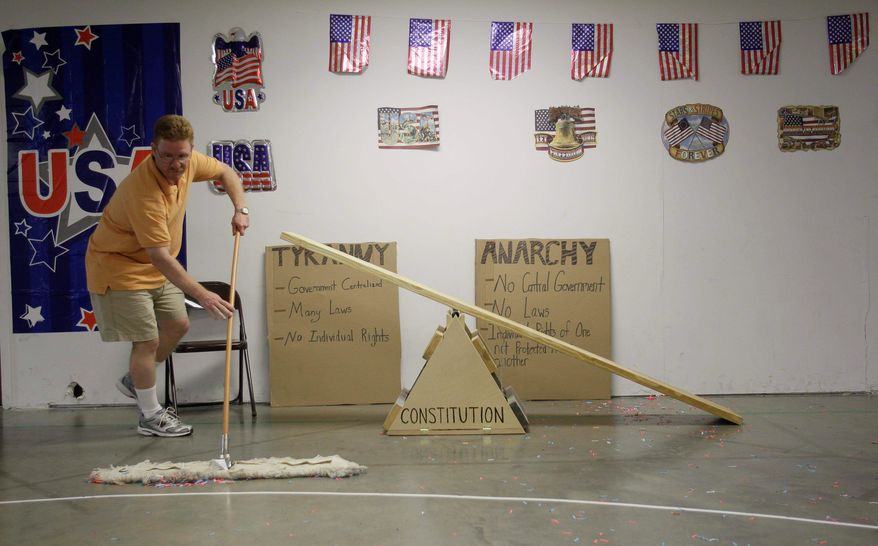 Dan Poorman sweeps up confetti in front of one of many displays during the first night of Vacation Liberty School. Students who made it to the New World found a room where they could play basketball, toss beanbags and ride a teeter-totter while being showered with confetti as Neil Diamond's "Coming To America" blared over the speakers.