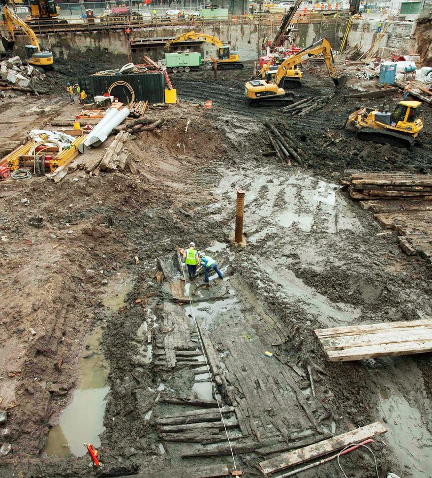 Associated Press photographs
Archeologists (above) take measurements of the wood hull of a 32-foot-long 18th-century boat found at the World Trade Center site and workers survey the planks sticking out of the mud. Archaeologists are racing to analyze the vessel before the delicate wood begins to deteriorate.