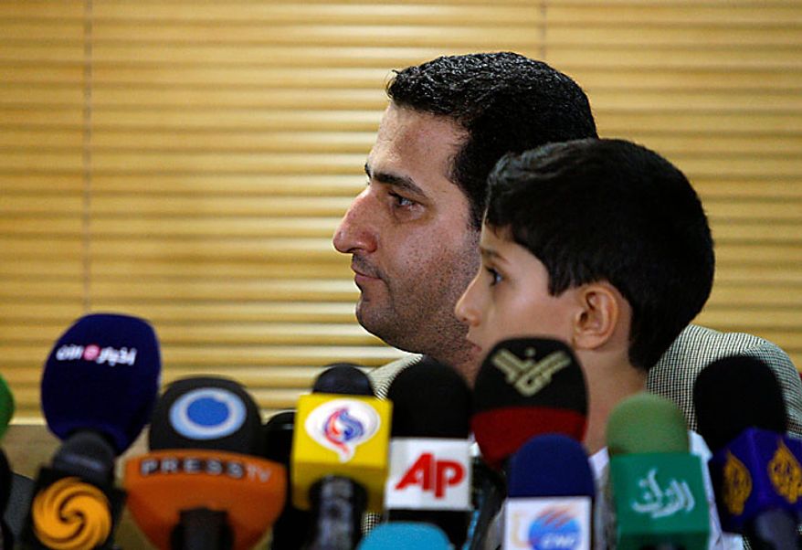 Shahram Amiri, an Iranian nuclear scientist who disappeared a year ago, listens to a question while holding his 7-year-old son Amir Hossein during a news briefing as he arrives at the Imam Khomeini airport just outside Tehran, Iran, Thursday, July 15, 2010. Mr. Amiri claimed Thursday he suffered extreme mental and physical torture at the hands of U.S. interrogators after disappearing last year, adding to Tehran's allegations he was abducted by American agents. (AP Photo/Vahid Salemi)