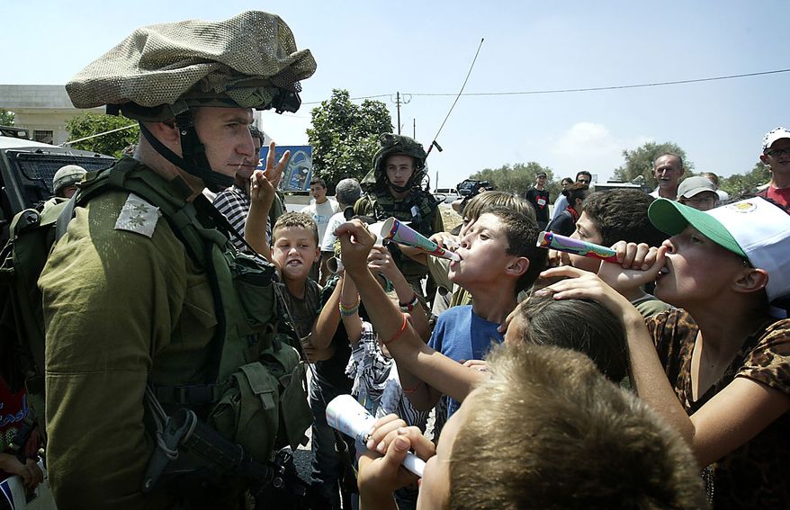 Palestinian youths taunt an Israeli officer during a demonstration against the expansion of the nearby Jewish settlement of Halamish in the West Bank village of Nabi Saleh near Ramallah, Friday, July 16, 2010. (AP Photo/Majdi Mohammed)