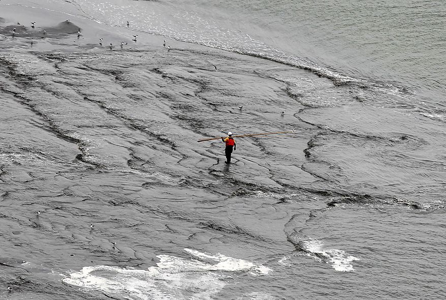 A worker walks through the water as a berm system is constructed on the northern end of the Chandeleur Islands, La., Thursday, July 15, 2010. A tightly fitted cap was successfully keeping oil from gushing into the Gulf of Mexico for the first time in three months, BP said Thursday. (AP Photo/Dave Martin)
