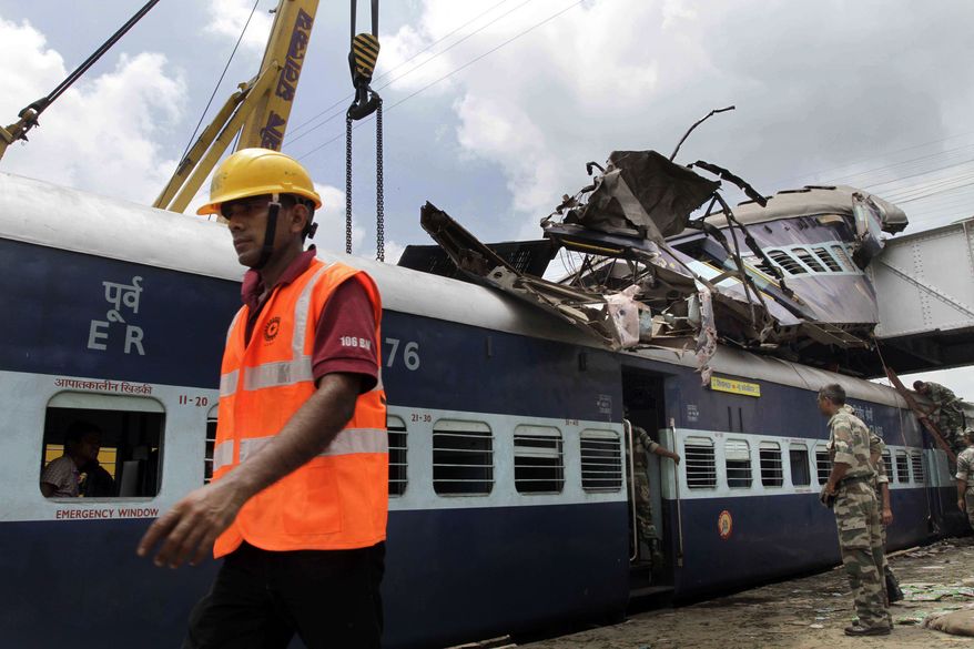 A rescue worker walks past the tangled trains following an accident at Sainthia station, about 125 miles north of Kolkata, India, on Monday, July 19, 2010. A speeding express train collided with a passenger train at the station in eastern India early Monday, mangling the carriages and killing 61 people, railway police said. (AP Photo/Bikas Das)
