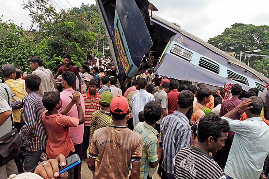 Local residents gather at the site of an accident at Sainthia station, about 125 miles (200 kilometers) north of Calcutta, India, Monday, July 19, 2010. A speeding express train collided with a passenger train at the station in eastern India early Monday, mangling the carriages and killing scores of people, railway police said. (AP Photo/Bikas Das)