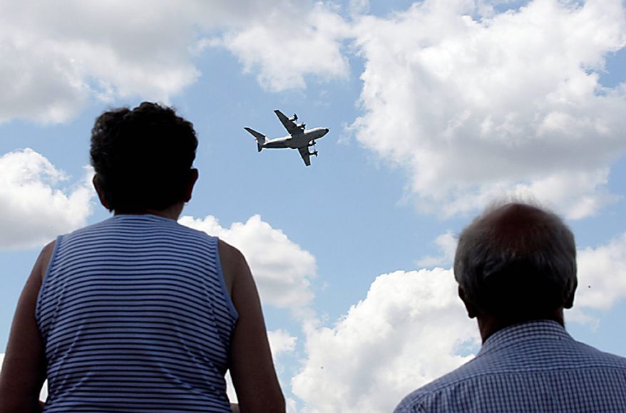Visitors watch an Airbus SAS A400M military transport plane fly on the third day of the Farnborough International Airshow in Farnborough, England, on Wednesday, July 21, 2010. The Farnborough International Airshow is being held from July 19-25. Photographer: Simon Dawson/Bloomberg