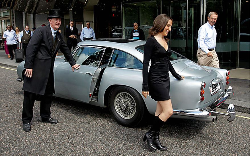 A woman walks away after modeling beside the original Aston Martin DB5 car driven by Sean Connery in the James Bond films Goldfinger and Thunderball as it displayed for the media in London, Wednesday, July 21, 2010. The car is estimated to fetch in the region of $4.6 million when it is sold at auction in London on Oct. 27. (AP Photo/Matt Dunham)