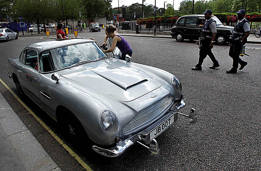 Traffic wardens walk past the original Aston Martin DB5 car driven by Sean Connery in the James Bond films Goldfinger and Thunderball as it displayed for the media in London, Wednesday, July 21, 2010. The car is estimated to fetch in the region of $4.6 million when it is sold at auction in London on Oct. 27. (AP Photo/Matt Dunham)