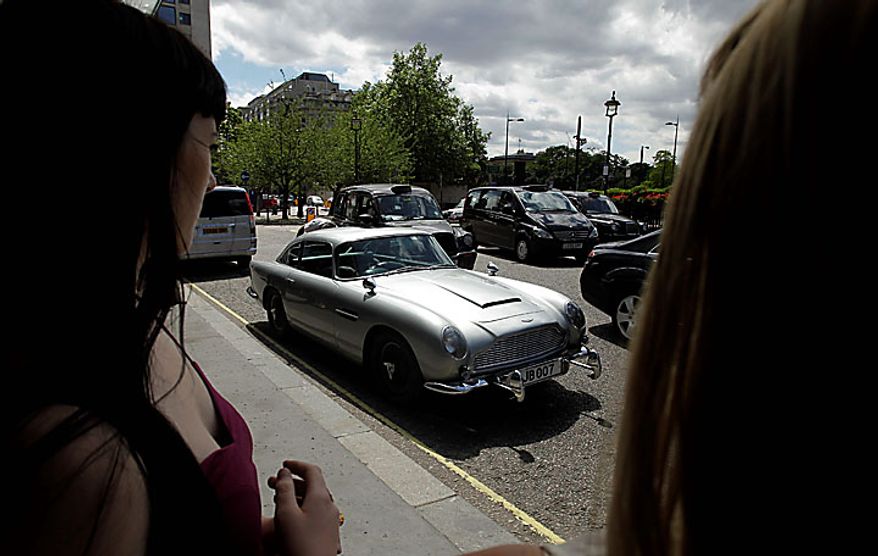 Women look at the original Aston Martin DB5 car driven by Sean Connery in the James Bond films Goldfinger and Thunderball as it displayed for the media in London, Wednesday, July 21, 2010. The car is estimated to fetch in the region of $4.6 million when it is sold at auction in London on Oct. 27. (AP Photo/Matt Dunham)