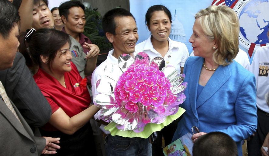 A man presents flowers to Secretary of State Hillary Rodham Clinton, right, after she signed a memorandum of understanding for U.S. support of HIV/AIDS programs in Vietnam, at Ngoc Lam Pagoda in Hanoi, Vietnam, on Thursday July, 22, 2010. (AP Photo/Julian Abram Wainwright, Pool)