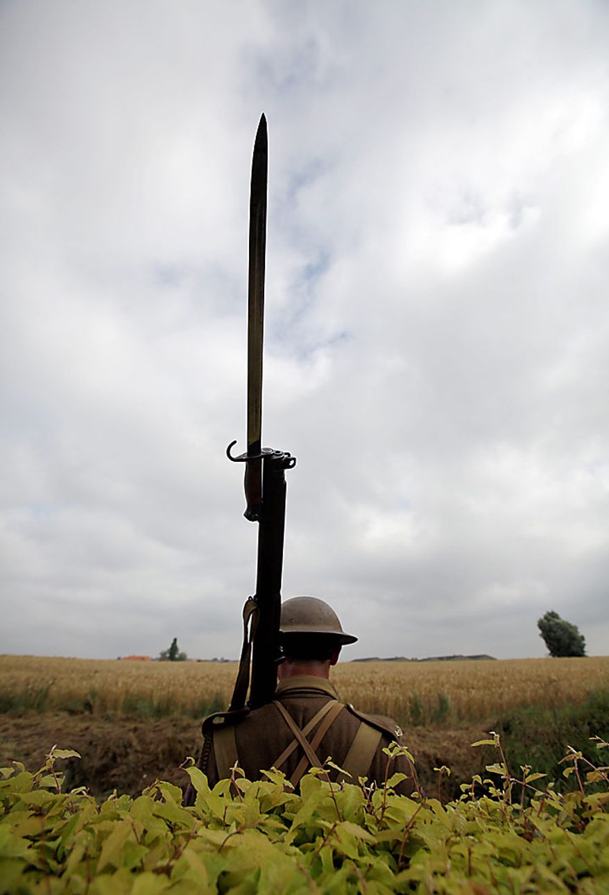 A man dressed in a World War One uniform stands guard outside the Prowse Point Cemetery during a re-burial ceremony for Australian World War One soldier, Private Alan James Mather in Ploegsteert, in Belgium on Thursday, July 22, 2010. Mr. Mather, originally from Invernell, NSW, Australia was one of 216,000 men from Australia, New Zealand and the UK who fought in the Battle of Messines from June 7-14, 1917. The body of Mr. Mather was discovered by a British archeological team in 2008, and further DNA tests by a Belgian laboratory revealed his full identity. (AP Photo/Virginia Mayo)