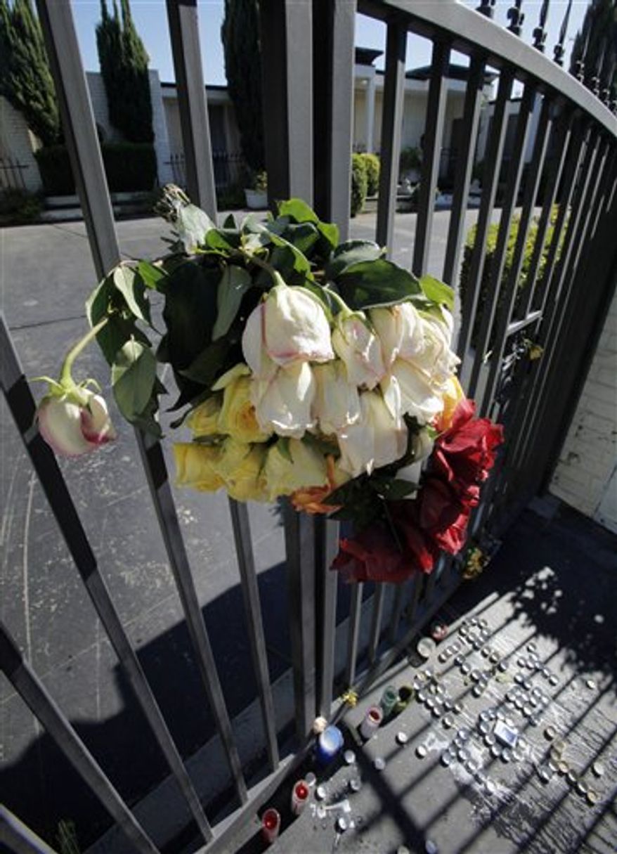 A bouquet is seen on a gate above a pattern of candles that spell "RIP TONY T" among other memorial items that have been placed outside a home where Katsutoshi "Tony" Takazato was stabbed to death, seen Thursday, July 22, 2010. Takazato is the son of Japanese movie producer Fuminori Hayashida, who owned the home where Takazato died Tuesday, July 20. (AP Photo/Reed Saxon)