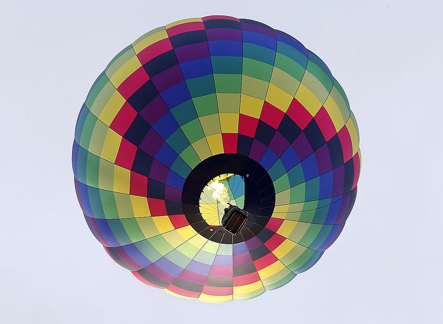 A hot air balloon flies in the early morning Friday, July 23, 2010, at the Quick Chek New Jersey Festival of Ballooning in Readington, N.J. The festival runs through Sunday, July 25, 2010. (AP Photo/ Mel Evans)