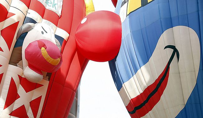 A cow and a clown come face to face as hot air balloons are inflated at the Quick Chek New Jersey Festival of Ballooning, Friday, July 23, 2010, in Readington, N.J. The festival runs through Sunday, July 25, 2010. (AP Photo/ Mel Evans)