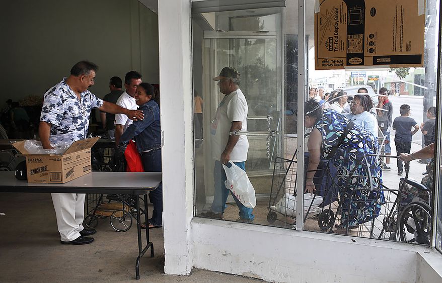 Mayor Oscar Hernandez, far left, greets people waiting in line for food at Bell Food Station in Bell, Calif., Thursday, July 22, 2010. The City Council in this small Los Angeles suburb is meeting Thursday to consider firing the police chief and two top administrators over their huge salaries, including Chief Administrative Officer Robert Rizzo who makes more than $787,000 a year, nearly twice the salary of President Barack Obama. Revelations about the pay in Bell has sparked anger in this blue-collar town that is one of the poorest in Los Angeles County. The council also will consider firing Assistant City Manager Angela Spaccia, who makes $376,288 a year, and Police Chief Randy Adams, whose annual salary of $457,000 is 50 percent more than that of Los Angeles Police Chief Charlie Beck. City officials, including Hernandez, have defended the salaries. (AP Photo/Jae C. Hong)