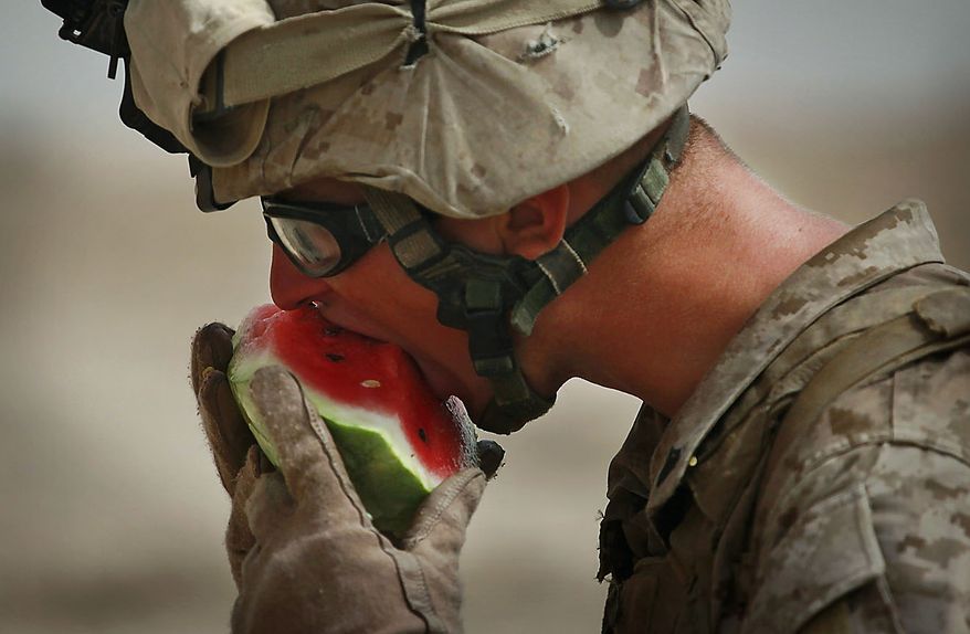 United States Marine Cpl. Ryan Farris from Bravo Company of the 1st Battalion of the 2nd Marines eats watermelon following a gunbattle as part of an operation to clear the area of insurgents near Musa Qaleh, in northern Helmand Province, southern Afghanistan, Friday, July 23, 2010. (AP Photo/Kevin Frayer)