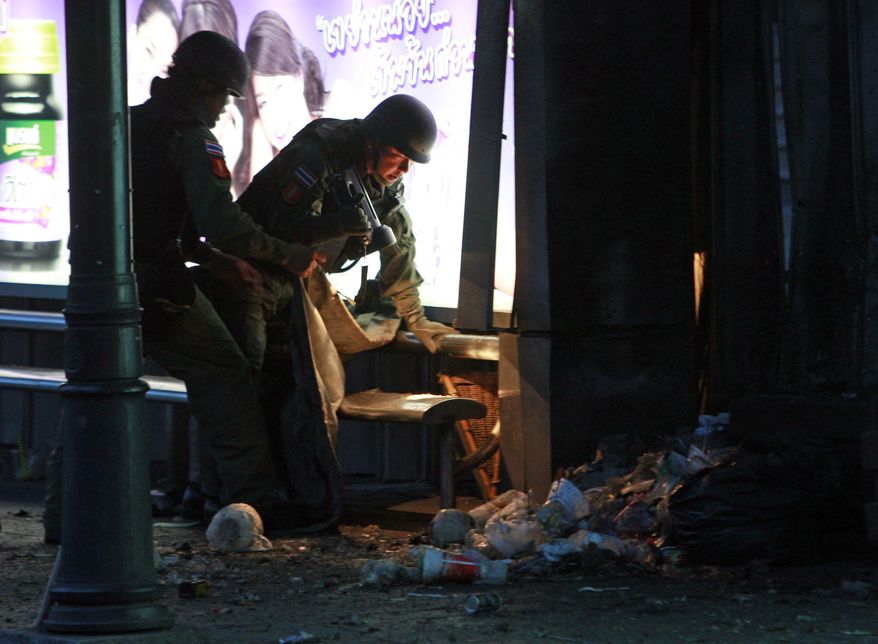**FILE** Thai bomb squad members examine the site of a bomb blast near a bus stop in downtown Bangkok on July 25, 2010. The bombing wounded nine people shortly after polls closed in a parliamentary election that pitted a government candidate against a jailed leader of recent mass protests in the Thai capital. (Associated Press)