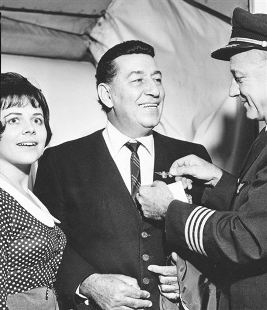 FILE - In this Sept. 3, 1965 file photo, jazz musician Louis Prima, center, accompanied by his wife Gia, left, receives a pin from a TWA crew member on the occasion of his first plane ride in New York City. The late 'King of Swing' Louis Prima has received the 2,413th star on the Hollywood Walk of Fame in a centennial celebration that included dancing in the street to his big-band sounds. The influential band leader was honored at a Sunday, July 25, 2010 ceremony on Vine Street attended by his son Louis Prima Jr., who continues the legacy of his father's music, his daughter Lena Prima, celebrities, dignitaries and fans. (AP Photo, File)