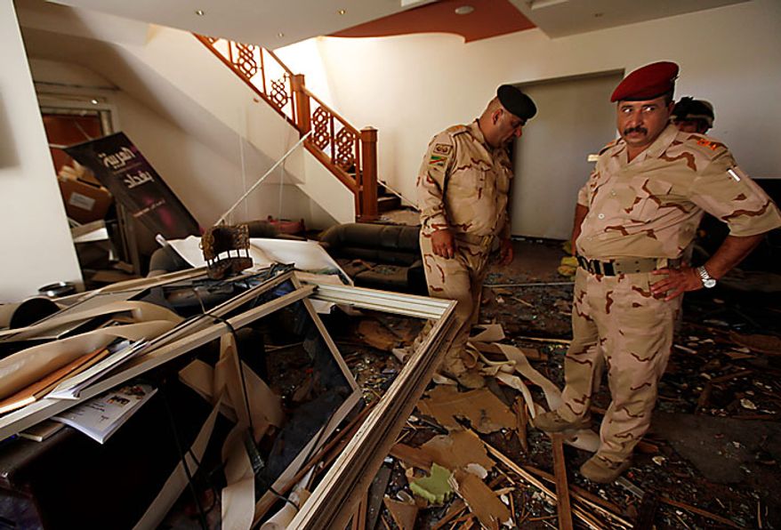 Iraqi army soldiers stand in the ruins of the office of the Al-Arabiya television station after a suicide bomber driving a minibus struck in Baghdad, Iraq, Monday, July 26, 2010. The bomber was apparently waved through the first checkpoint at the Al-Arabiya television station after security guards checked his identification, said Iraqi military spokesman Maj. Gen. Qassim al-Moussawi. The blast killed and injured several people at the popular Arabic-language satellite news channel early Monday. (AP Photo/Hadi Mizban)