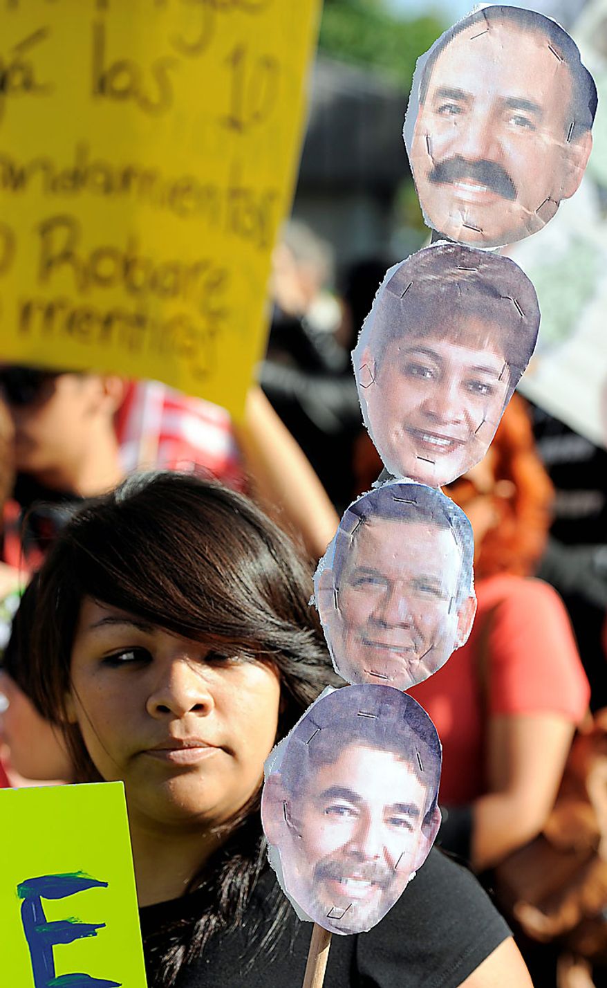 Bell, Calif., resident Vanessa Moya, 15, holds up paper cut-outs of Bell city officials as she awaits a city council meeting addressing city leaders' pay, Monday, July 26, 2010, in Bell, Calif. (AP Photo/Chris Pizzello)