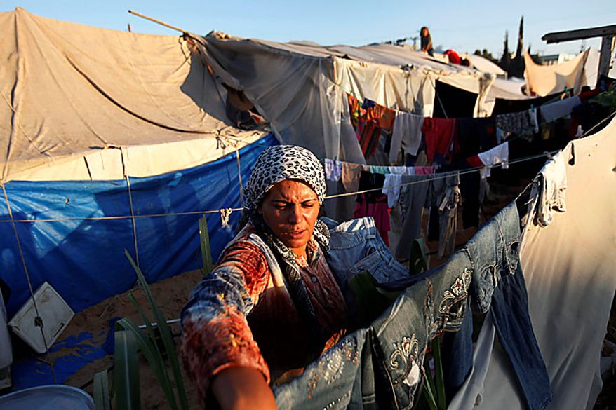 Palestinian Wafa Awaja, 34, collects her family's laundry outside the tents that serve to house her family in Beit Lahiya, northern Gaza Strip, Thursday, June 10, 2010. The Awajas are among thousands of families whose houses were destroyed during Israel's three-week military offensive against Hamas-ruled Gaza, launched in December 2008 with the aim of halting Hamas rocket attacks. An Israeli forces bulldozer flattened the Awajas' house and as the family tried to flee, bullets hit Wafa, her husband Kamal and their 8-year-old son Ibrahim, who bled to death in the street. (AP Photo/Lefteris Pitarakis)