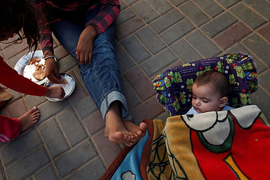 Five month-old Palestinian girl Leyali Awaja sleeps in the makeshift structures that house her family as her siblings Omsyat and Hala eat their lunch, in Beit Lahiya, northern Gaza Strip, Thursday June 10, 2010. The Awajas are among thousands of families whose houses were destroyed during Israel's three-week military offensive against Hamas-ruled Gaza, launched in December 2008 with the aim of halting Hamas rocket attacks. An Israeli forces bulldozer flattened the Awajas' house and as the family tried to flee, bullets hit Leyali's father Kamal, mother Wafa, and 8-year-old brother Ibrahim, who bled to death in the street. (AP Photo/Lefteris Pitarakis)