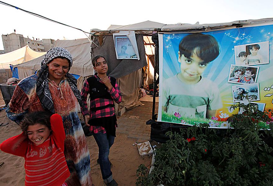 Palestinian Wafa Awaja, 34, jokes with her daughters Hala, 8, left, and Omsyat, 13, as they stand near the makeshift structures that house the family in Beit Lahiya, northern Gaza Strip, Thursday, June 10, 2010. A portrait of Wafa's late 8-year-old son Ibrahim _ killed during an Israeli army operation_ is attached to the tent at right. The Awajas are among thousands of families whose houses were destroyed during Israel's three-week military offensive against Hamas-ruled Gaza, launched in December 2008 with the aim of halting Hamas rocket attacks. An Israeli forces bulldozer flattened the Awajas' house and as the family tried to flee, bullets hit Wafa, her husband Kamal, and Ibrahim, who bled to death in the street. (AP Photo/Lefteris Pitarakis)