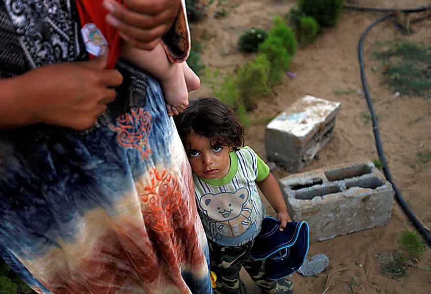 Palestinian Wafa Zikrayat, 2, stands next to her mother Wafa, 34, holding baby Leyali, near the makeshift structures that house the family in Beit Lahiya, northern Gaza Strip, Thursday, June 10, 2010. The Awajas are among thousands of families whose houses were destroyed during Israel's three-week military offensive against Hamas-ruled Gaza, launched in December 2008 with the aim of halting Hamas rocket attacks. An Israeli forces bulldozer flattened the Awajas' house and as the family tried to flee, bullets hit father Kamal, his wife Wafa, and their 8-year-old son Ibrahim, who bled to death in the street. (AP Photo/Lefteris Pitarakis)