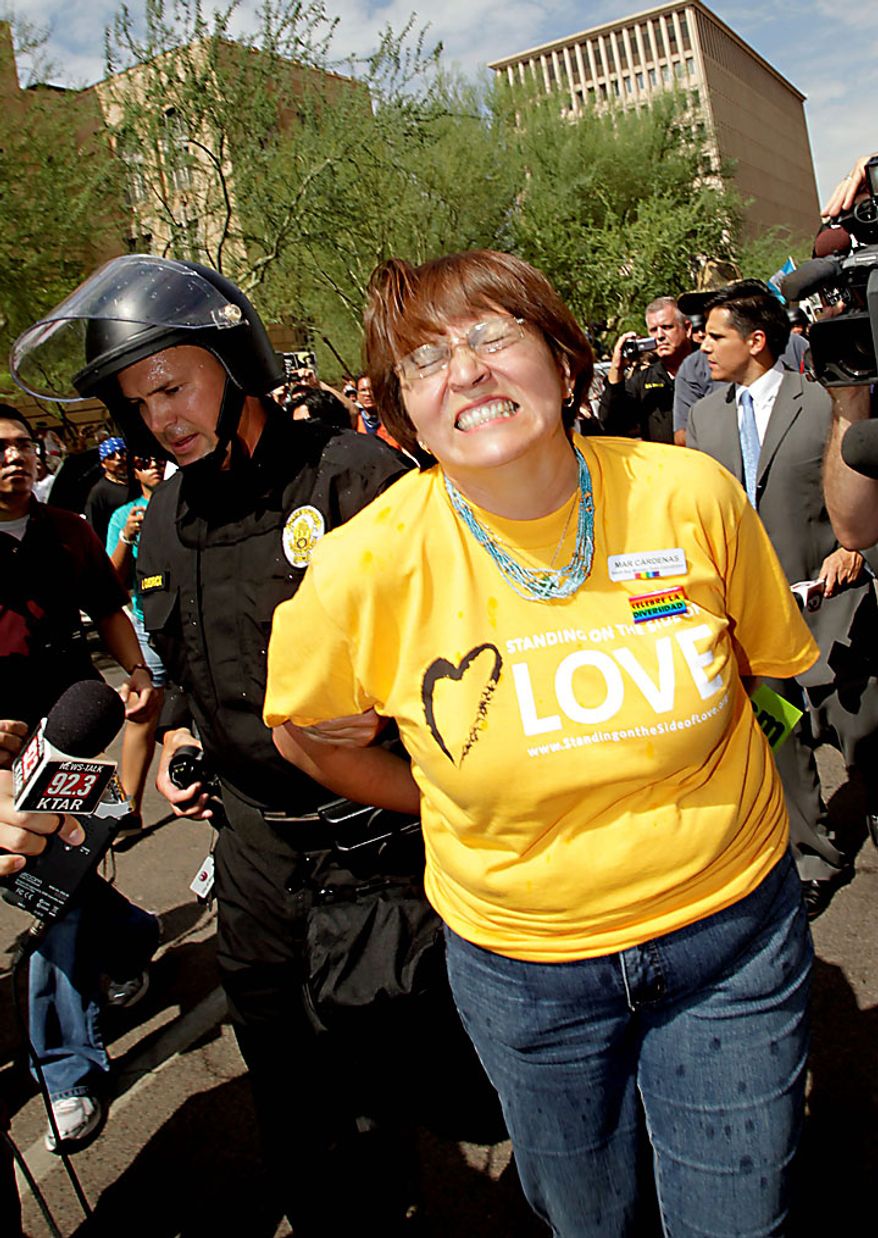 A protester is arrested Thursday, July 29, 2010 in Phoenix while rallying against Arizona's new immigration law, SB1070. Opponents of Arizona's immigration crackdown went ahead with protests Thursday despite a judge's ruling that delayed enforcement of most the law. (AP Photo/Matt York)