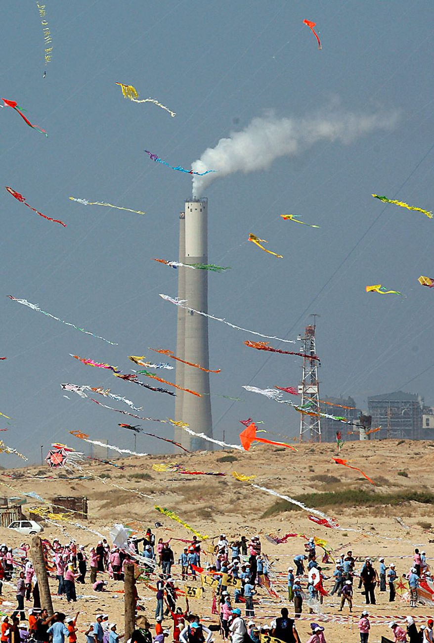 Thousands of Palestinian children in Beit Lahiya, Gaza Strip, fly kites in an attempt to break the world record for the number of kites flying simultaneously. More than 7,200 kites were raised into the air on Thursday, July 29, 2010, setting a new world record in an event sponsored by the United Nations. In the background are the chimneys of the Ashkelon power station. (AP Photo/Khalil Hamra)